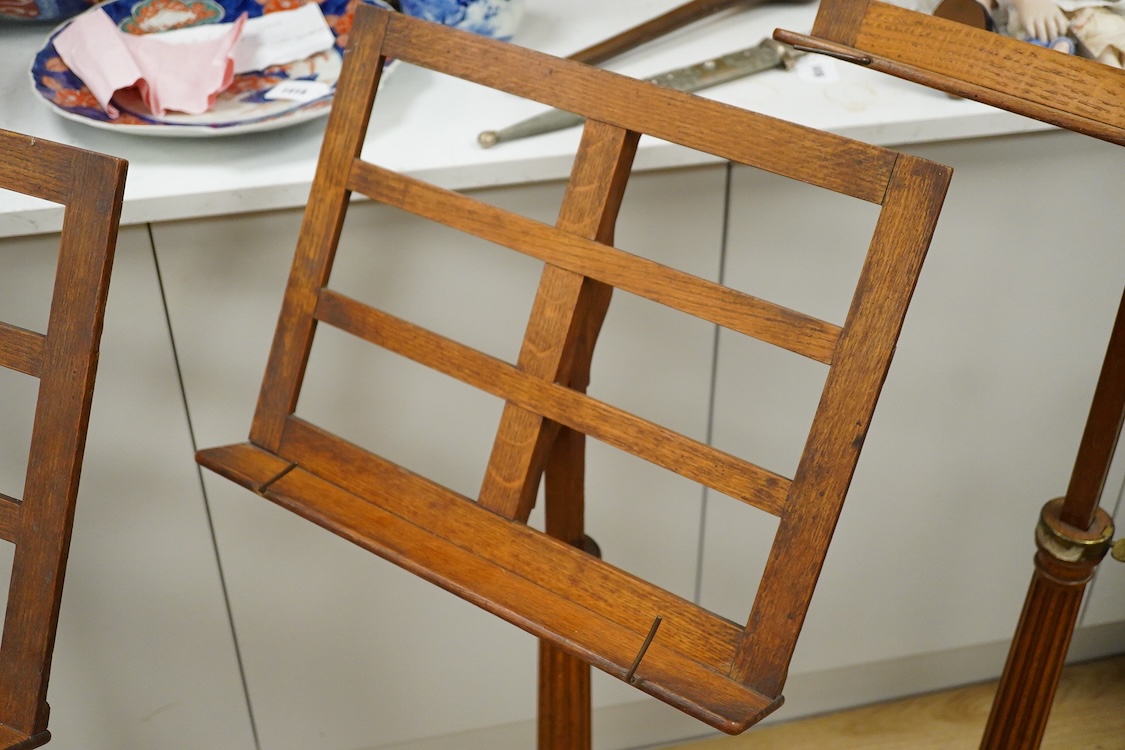A set of three early 20th century oak music stands, all with fluted pedestal supports and tripod legs with brass feet, adjustable height music desks, maximum overall height when extended 137cm, the angle of the desks is